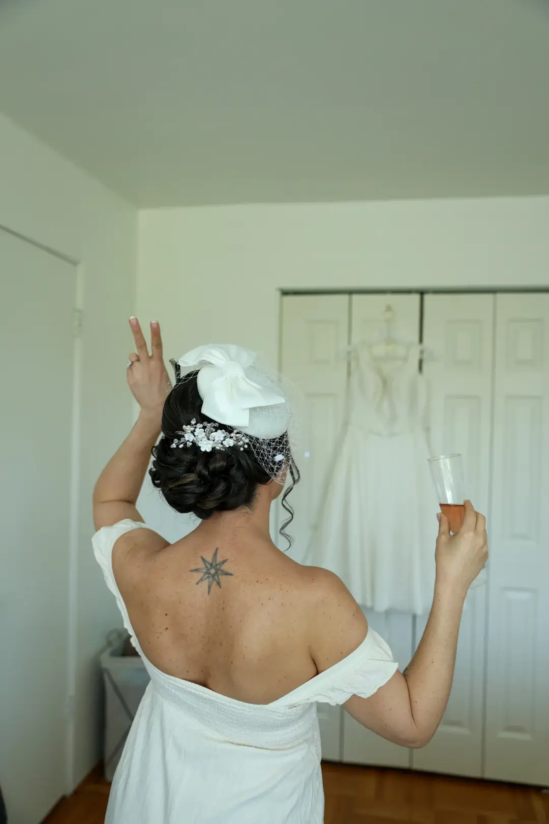 Rear view of a bride's dark low updo with a white flower and birdcage veil