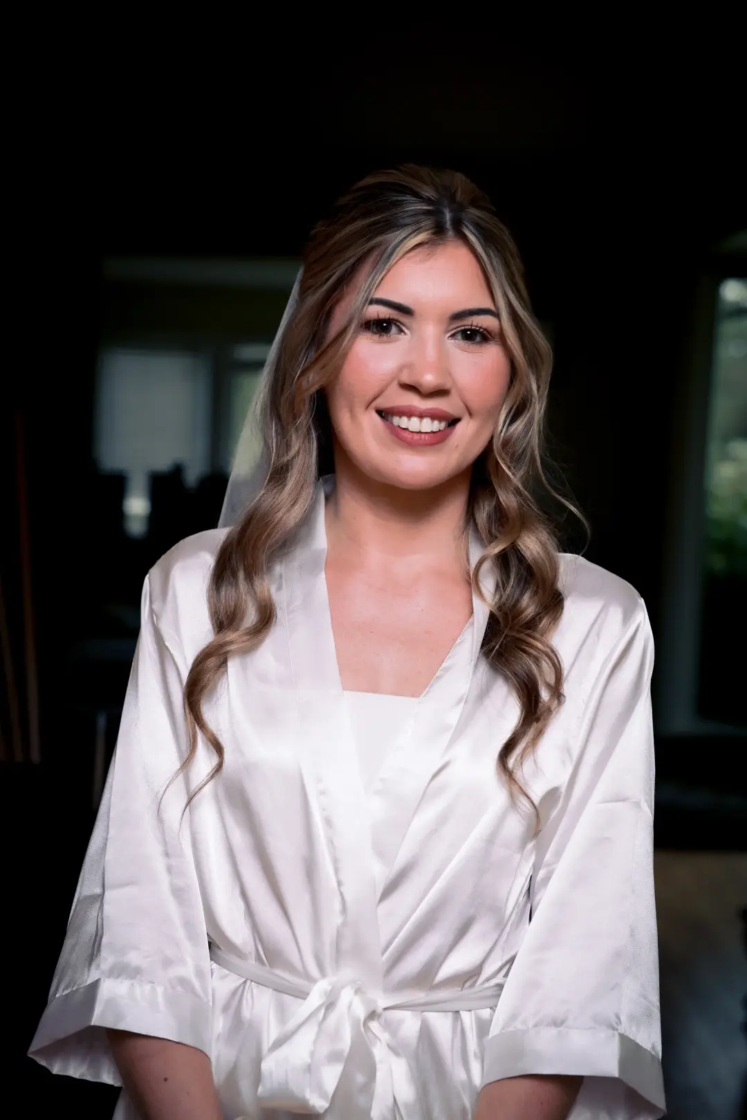 Smiling bride with long brunette waves and polished natural makeup