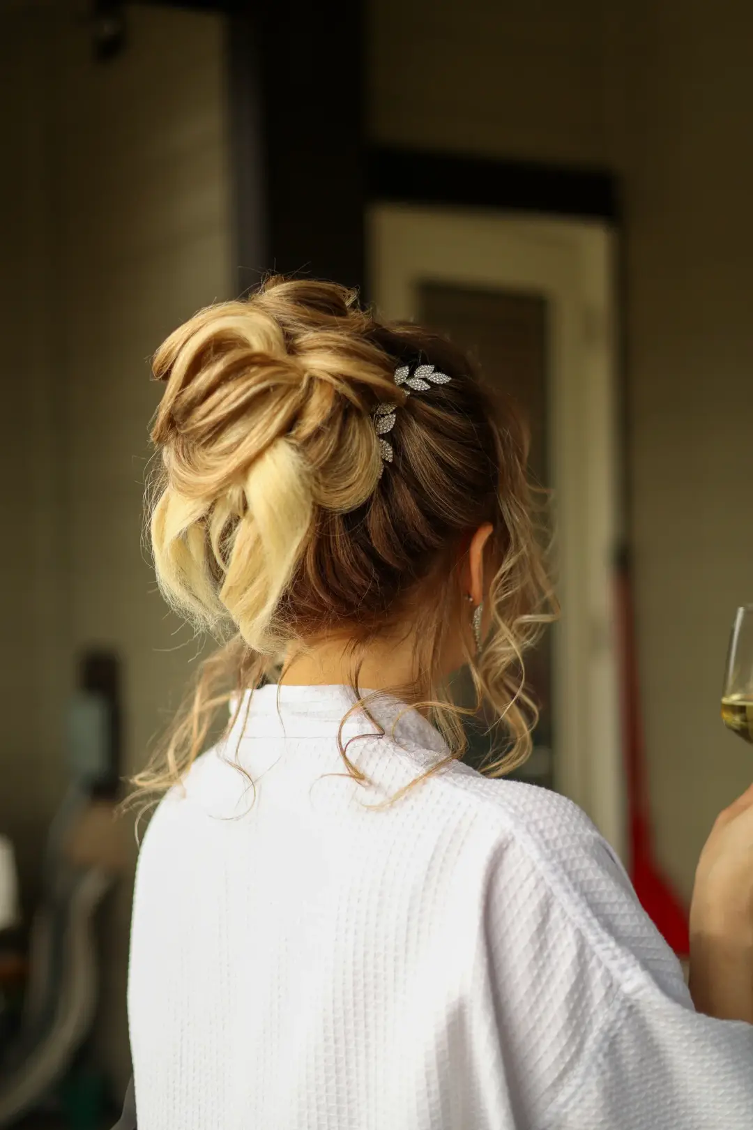 Looped blonde updo with a silver rhinestone leaf hairpiece
