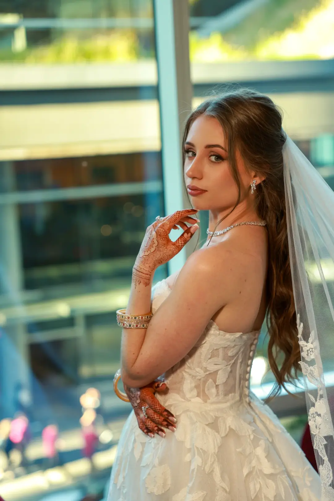 Bride with half-up brunette waves, a white veil, and softly defined makeup