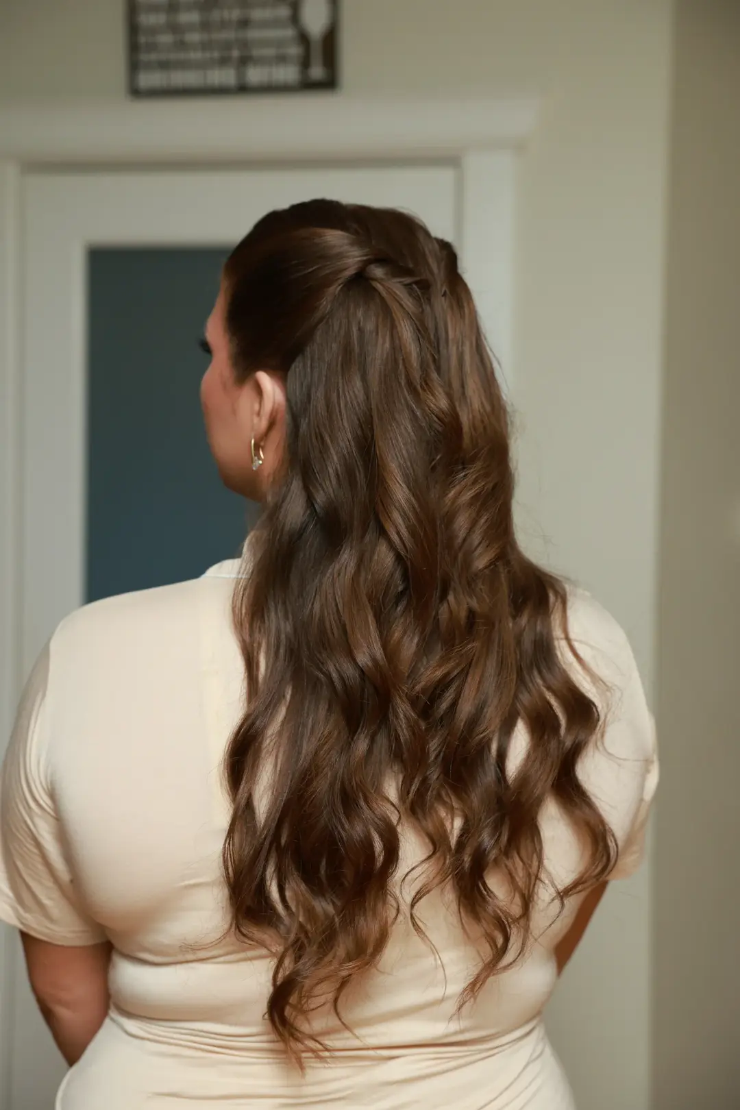 Long brunette waves gathered into a high half-up ponytail