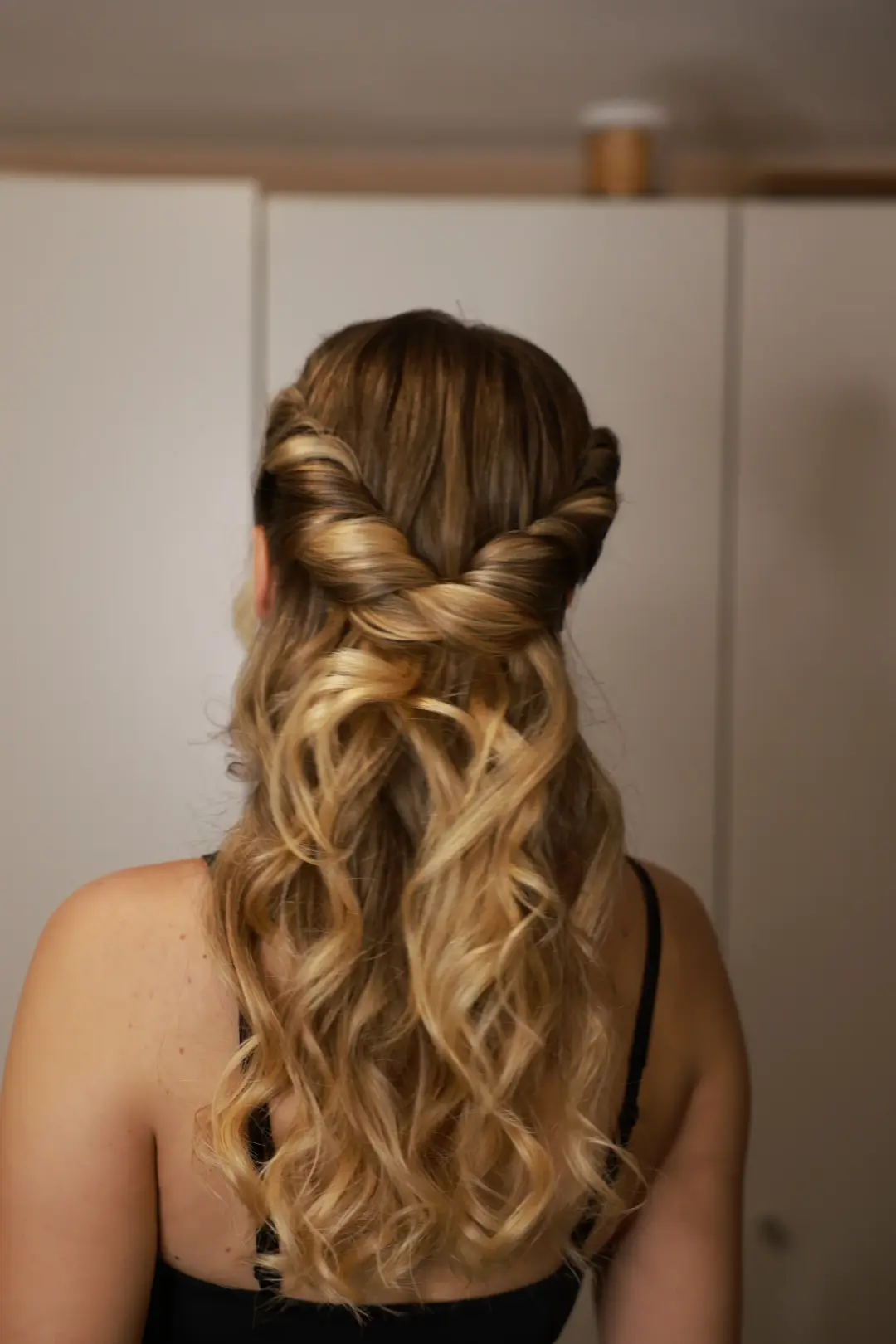 Half-up blonde hairstyle with twisted sides and long defined curls