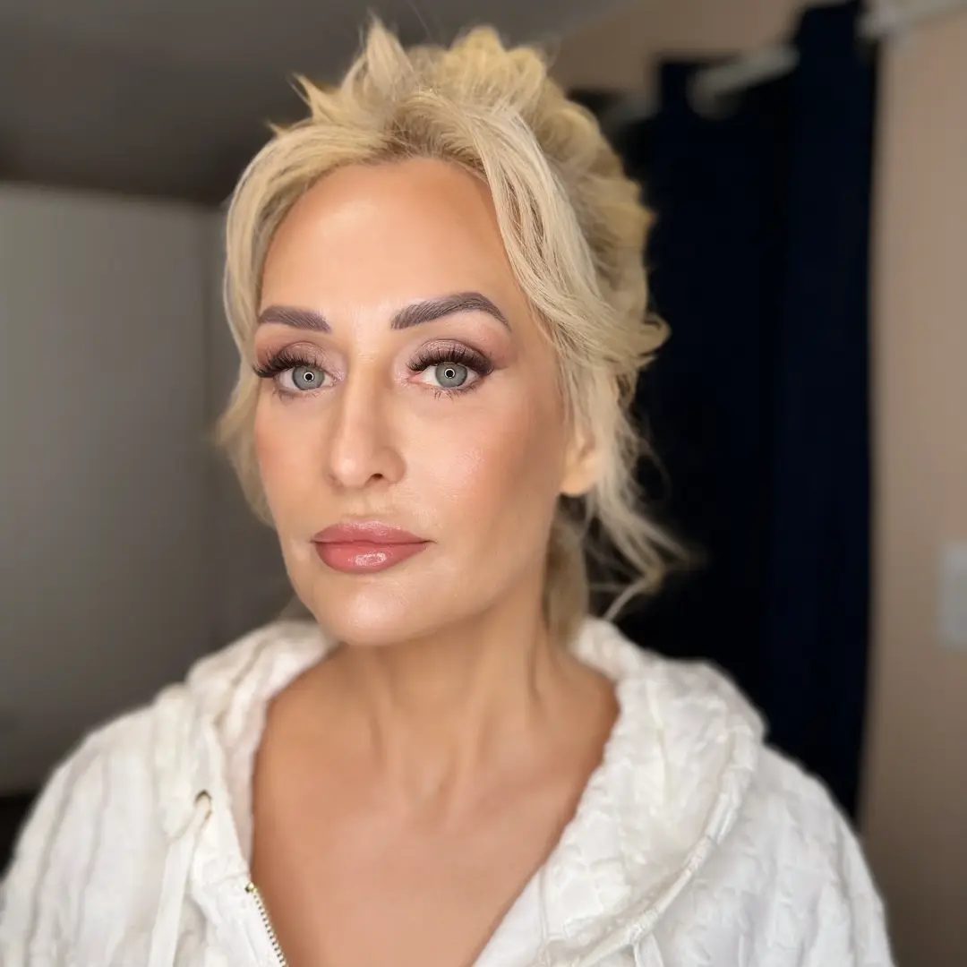 Blonde woman with a wispy updo and smoky rose evening makeup