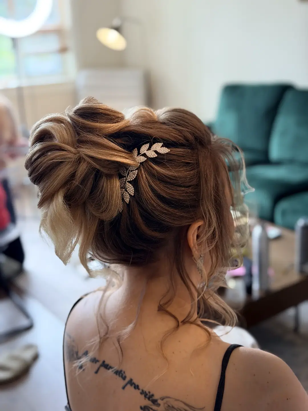 Textured auburn updo with a gold leaf hair pin and loose tendrils