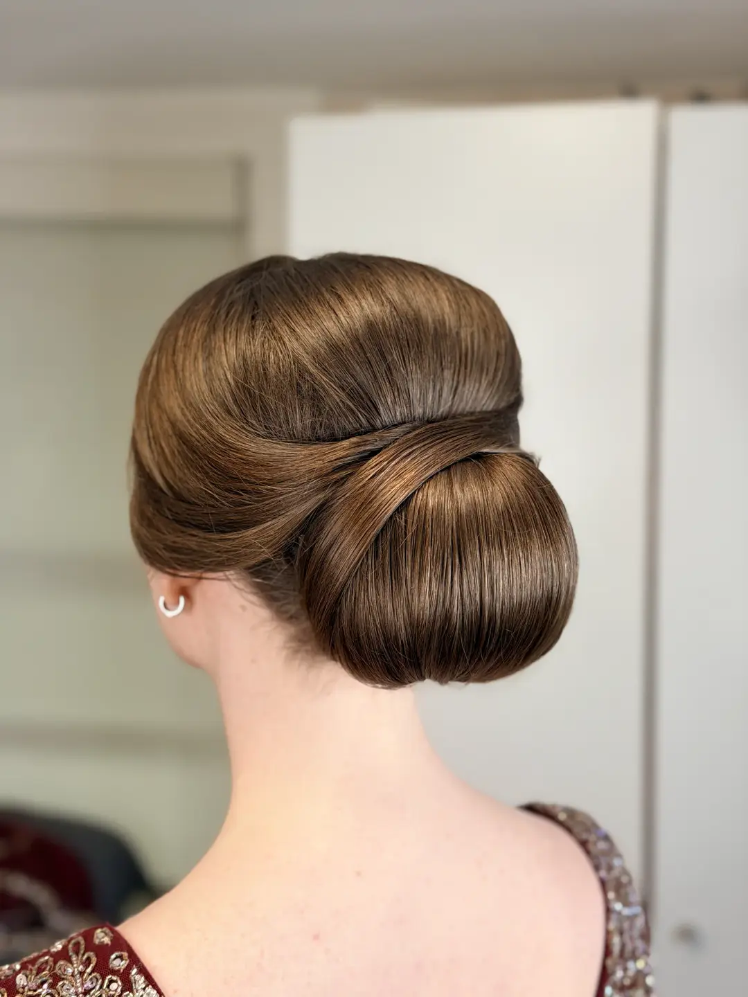 Sleek brunette low chignon with a smooth wrapped finish