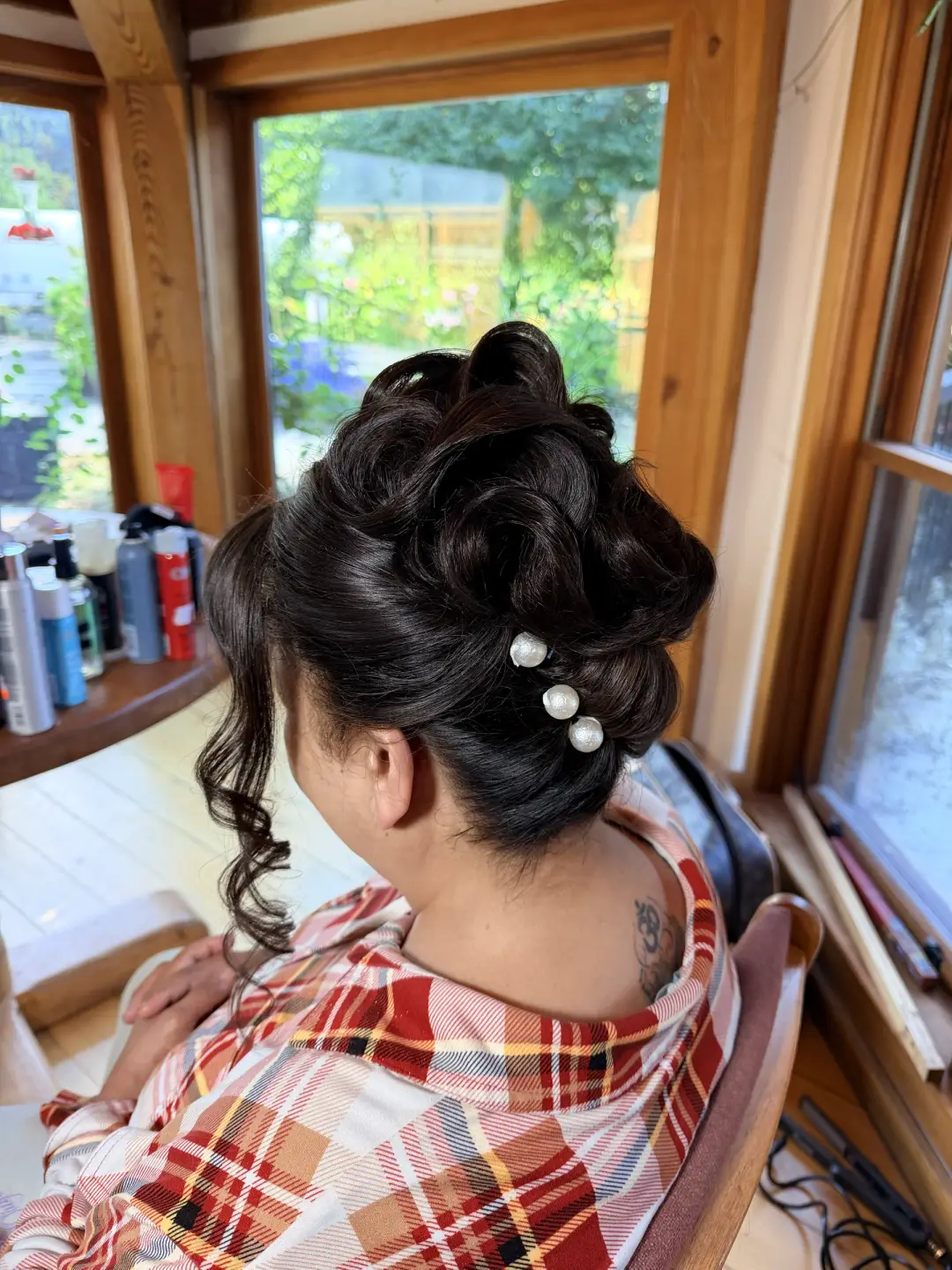 Voluminous dark updo with pearl pins and a loose side curl