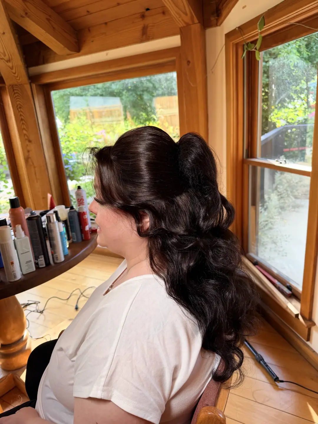High brunette ponytail with full soft curls, shown from the side