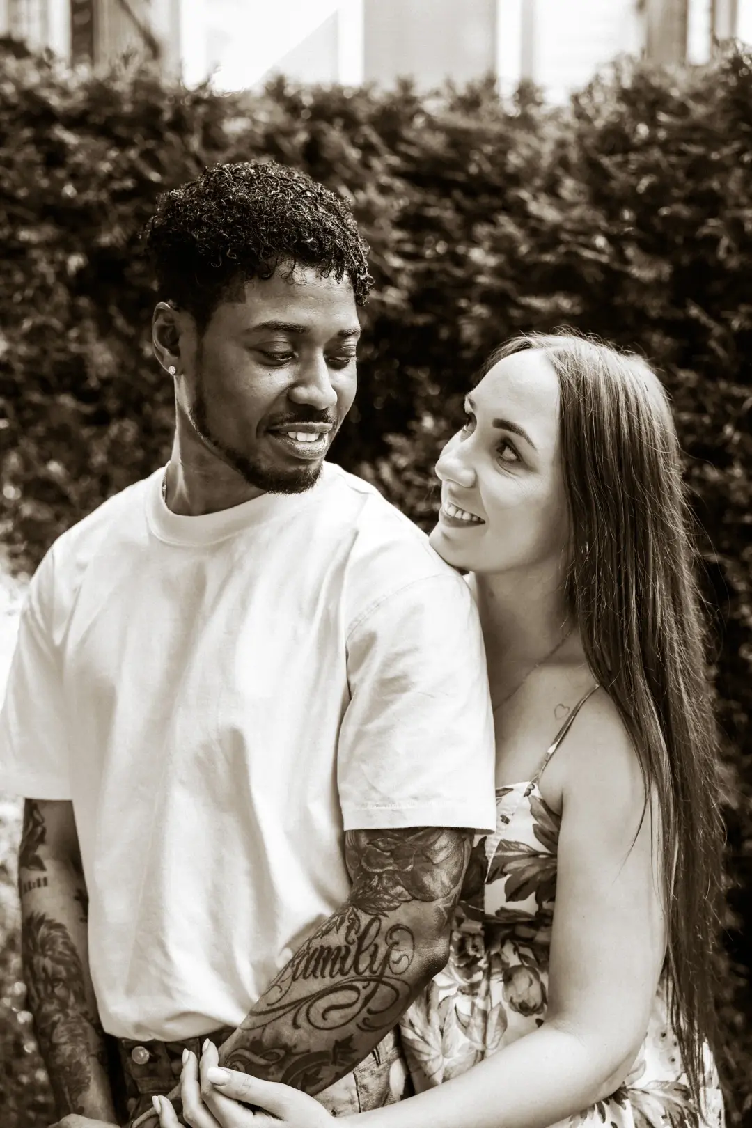 A couple smiling at each other with hands clasped between them, rendered in warm sepia tones.