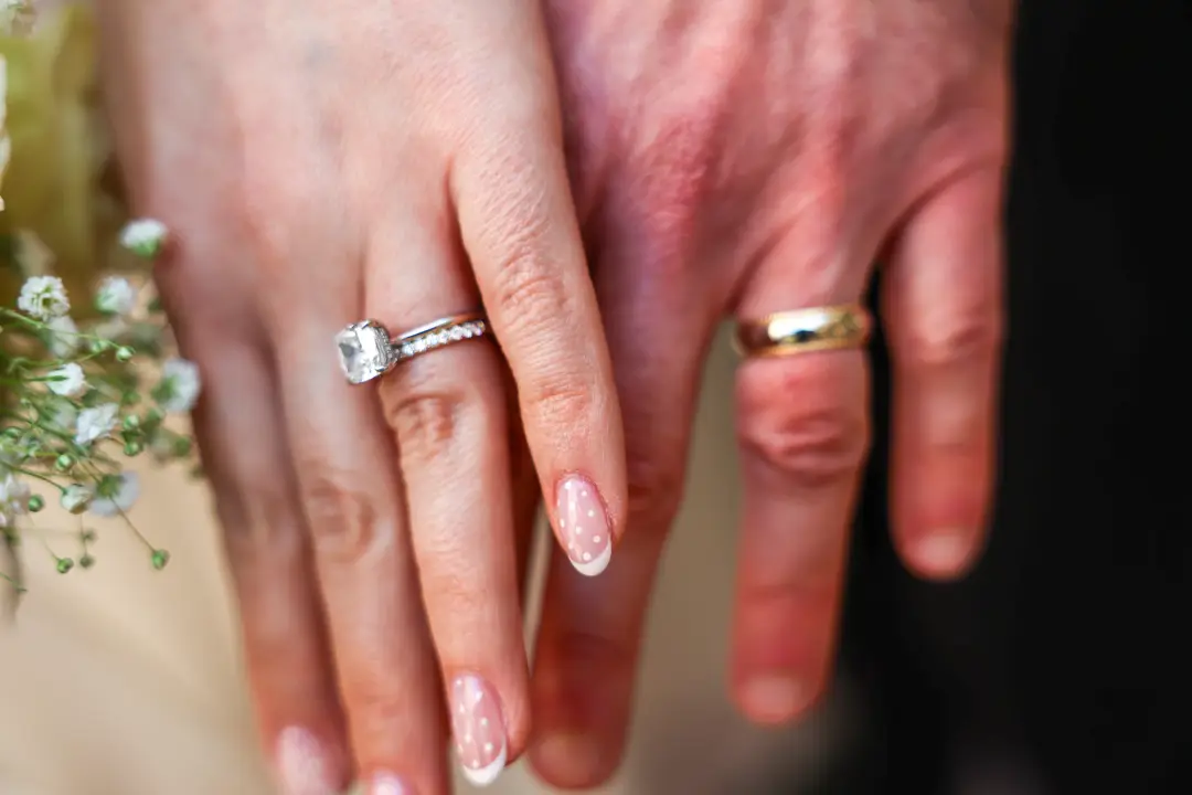 An intimate close-up of the newlyweds' hands and rings beside a spray of baby's breath.