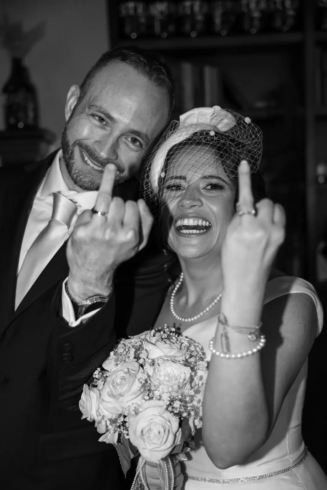 A playful black-and-white portrait of the newlyweds laughing closely together.